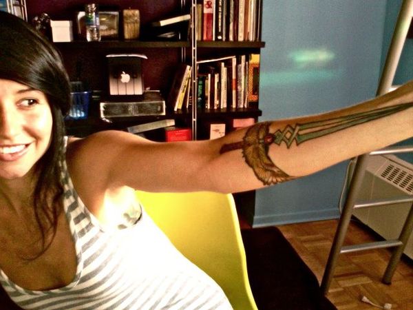 the Twinblade of the Phoenix from World of Warcraft on her left arm